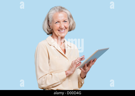 Portrait of senior woman using tablet PC contre fond bleu Banque D'Images