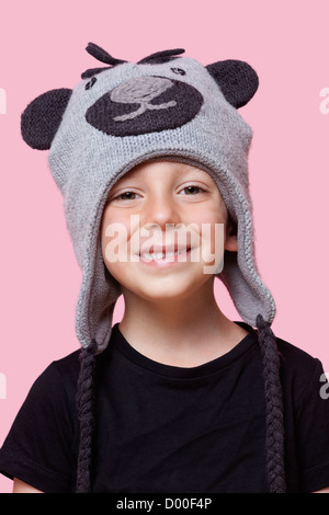 Portrait of a young boy wearing monkey cap sur fond rose Banque D'Images