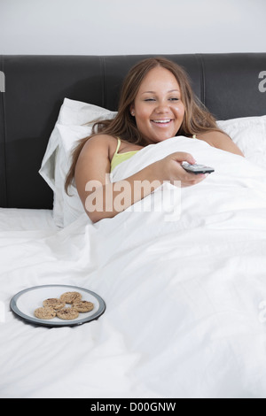 Happy young woman femme enceinte tout en regardant la télévision au lit à la maison Banque D'Images