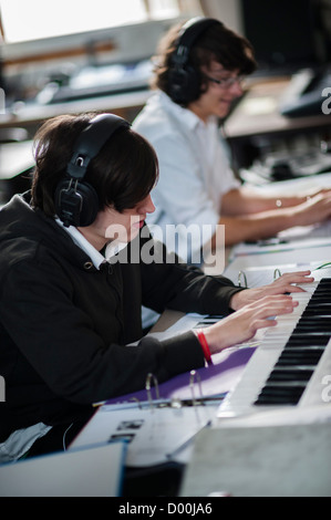 Deux adolescents jouant du piano claviers dans une sixième forme musicale à une leçon de classe à l'école secondaire, le Pays de Galles UK Banque D'Images