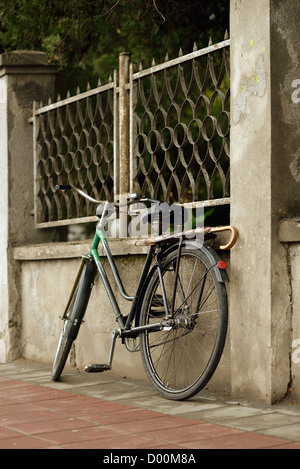 Vieux vélo dans la rue, appuyé sur le mur Banque D'Images