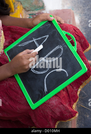 Village indien fille alphabet anglais écrit sur une ardoise dans une maison de village de l'Inde rurale porte. L'Andhra Pradesh, Inde Banque D'Images