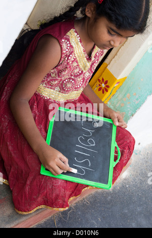 Village indien fille d'écrire le mot anglais sur le tableau dans une maison de village de l'Inde rurale porte. L'Andhra Pradesh, Inde Banque D'Images