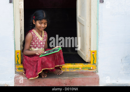 Village indien fille alphabet anglais écrit sur une ardoise dans une maison de village de l'Inde rurale porte. L'Andhra Pradesh, Inde Banque D'Images