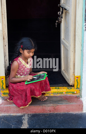 Village indien fille alphabet anglais écrit sur une ardoise dans une maison de village de l'Inde rurale porte. L'Andhra Pradesh, Inde Banque D'Images