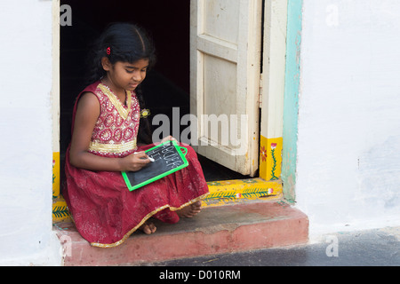 Village indien fille alphabet anglais écrit sur une ardoise dans une maison de village de l'Inde rurale porte. L'Andhra Pradesh, Inde Banque D'Images