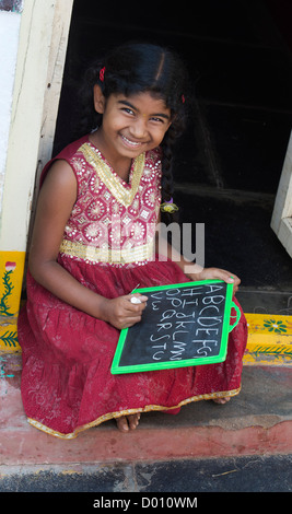 Village indien fille alphabet anglais écrit sur une ardoise dans une maison de village de l'Inde rurale porte. L'Andhra Pradesh, Inde Banque D'Images