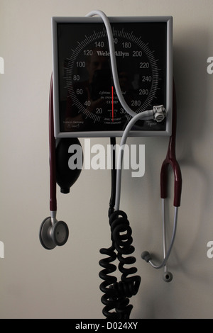 Un instrument de pression artérielle Moniteur de jauge sur un mur dans un hôpital avec un stéthoscope pendu à elle Banque D'Images