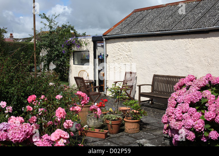 Joli jardin pavé ensoleillé avec hortensias, patio et cache-pots. Rose ! Banque D'Images