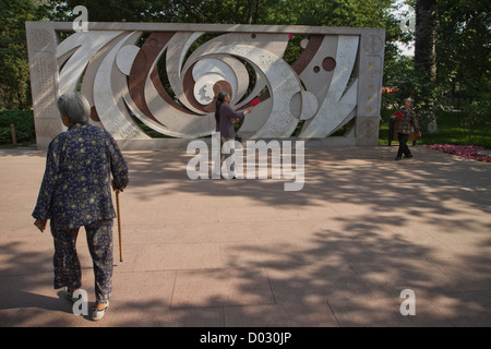 Une femme avec un bâton de marche en arrière deux femmes jouant volants dans un parc à Pékin, en Chine. Banque D'Images