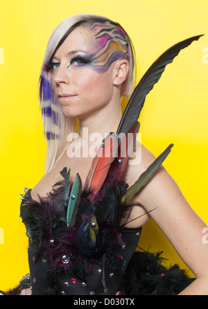 Femme aux cheveux multicolores, des plumes et des yeux bleus sur fond jaune Banque D'Images