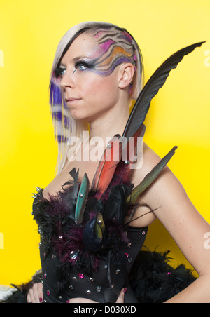 Femme aux cheveux multicolores, des plumes et des yeux bleus sur fond jaune Banque D'Images