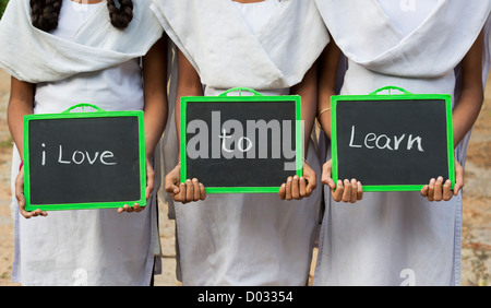 Trois filles de l'école de village indien avec J'aime apprendre écrit sur un tableau. L'Andhra Pradesh, Inde Banque D'Images