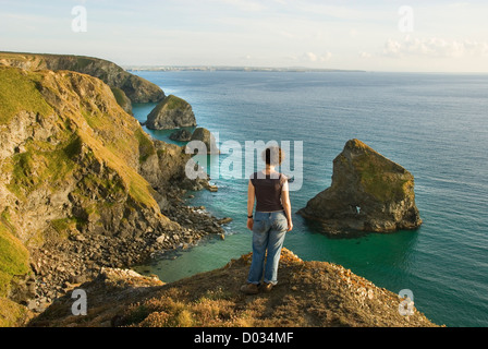 Femme à la recherche de roches et de littoral, plage submergée à marée haute, Bedruthan Steps, Carnewas, Cornwall, England, UK Banque D'Images