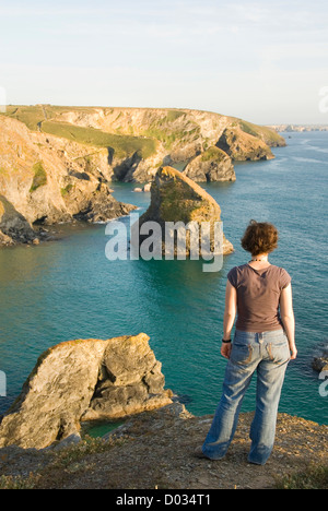 Femme à la recherche de roches et de littoral, plage submergée à marée haute, Bedruthan Steps, Carnewas, Cornwall, England, UK Banque D'Images