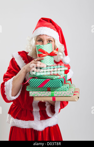 Studio portrait of Santa Claus holding elf helper et de peering de derrière des cadeaux de Noël Banque D'Images