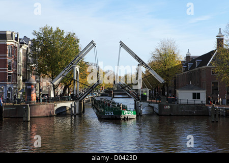 Une péniche passe par un pont ouvert au centre d'Amsterdam. Banque D'Images