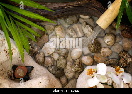 L'eau qui tombe sur des pierres spa concept historique d'orchidées et de bambou Banque D'Images