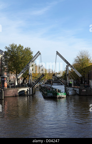 Une péniche passe par un pont ouvert au centre d'Amsterdam. Banque D'Images