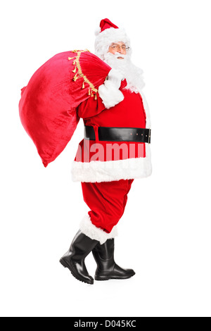 Portrait d'un père Noël marche avec sac plein de cadeaux et son dos isolé sur fond blanc Banque D'Images