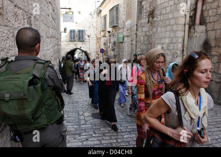 Des soldats israéliens montent la garde comme un groupe de pèlerins chrétiens à pied le long de la Via Dolorosa street que l'on croit être le chemin que Jésus a marché sur le chemin de sa crucifixion dans la vieille ville. Jérusalem est, Israël Banque D'Images