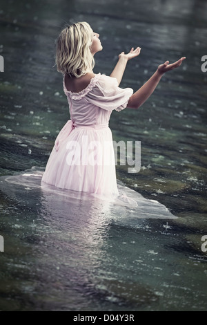 Une femme debout dans l'eau et profiter de la pluie