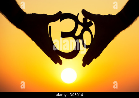 Mains tenant le symbole AUM OM / hindou au coucher du soleil. L'Inde. Silhouette Banque D'Images