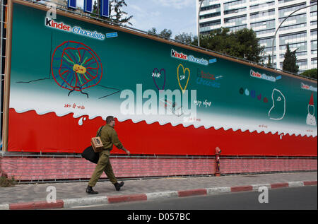 Un soldat de réserve israélien portant une boîte de masque à gaz passe devant un panneau publicitaire annonçant Kinder Chocolate dans le centre-ville de tel Aviv Israël Banque D'Images