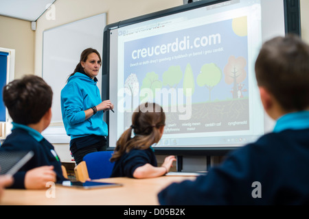 Une enseignante à l'aide d'un tableau blanc interactif dans une leçon de gallois à une nouvelle communauté de l'école primaire de Galles UK Banque D'Images