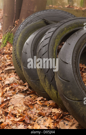 Déchets Pollution pneus de voiture à tête de dumping par campagne et formant une maison pour la faune en partie recouverte d'algues Banque D'Images