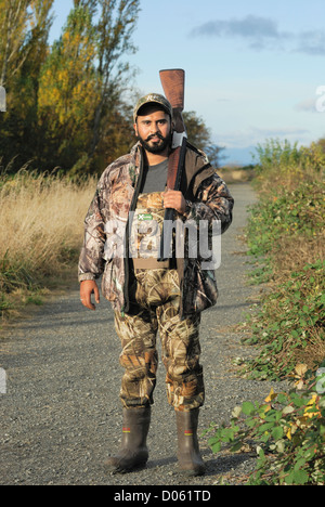 Duck hunter de camouflage avec son fusil sur son épaule. Banque D'Images