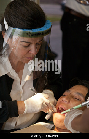 Dentiste bénévole féminin fournit des services dentaires par une mission clinique dentaire mobile sourit à Tampa, FL Banque D'Images