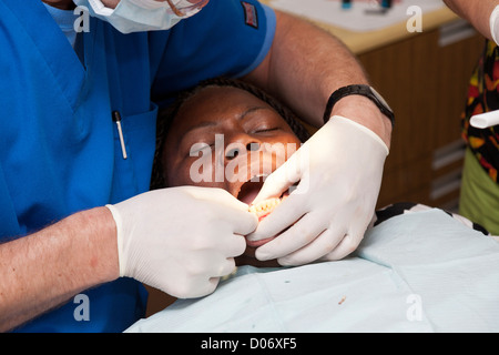 Bénévole masculin blanc et dentiste assistant services pour femme noire par une Mission Smiles clinique mobile à Tampa, FL Banque D'Images