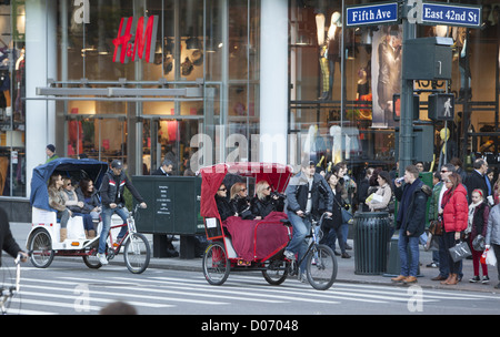 Les touristes ont un bon moment voir Manhattan dans pedeicabs sur la 5e Avenue à la 42e Rue à New York City. Banque D'Images