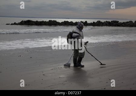 Man combs la plage de Coney Island avec un détecteur de métal dans l'espoir que l'Ouragan Sandy a mis en place certains trésors enfouis. Banque D'Images