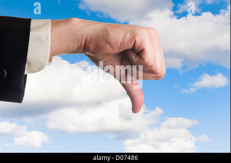 Mans hand, les pouces vers le bas, le fond de ciel nuageux. Banque D'Images