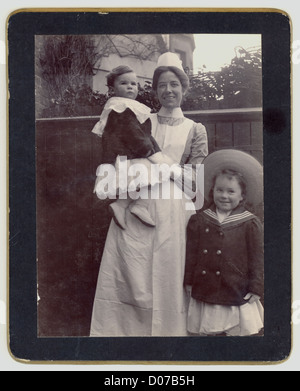 Carte originale de l'armoire édouardienne représentant un gai et attrayant nursemaid ou femme de chambre de bébé avec des enfants, portraits professionnels vers 1905, Royaume-Uni Banque D'Images