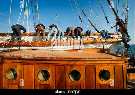 Les membres d'équipage à bord de la goélette historique 'zodiac' mettez de côté les voiles après une course de voilier à Port Townsend, Washington, USA. Banque D'Images