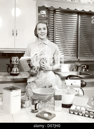 Woman with apron holding cookbook Banque D'Images