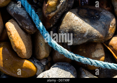 Un gros plan de cordage en nylon bleu sur une plage de galets Banque D'Images