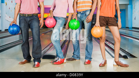 Deux jeunes couples holding bowling balls dans un bowling Banque D'Images