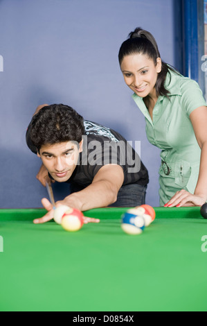 Jeune homme jouant au billard et une jeune femme en regardant son jeu Banque D'Images