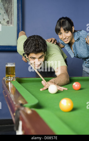 Jeune homme jouant au billard et une jeune femme en regardant son jeu Banque D'Images