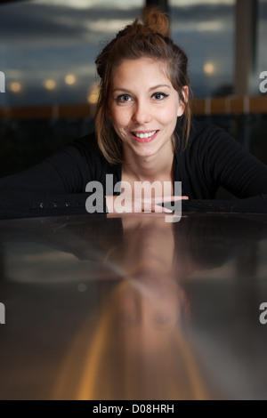 Belle femme à la recherche avec un grand sourire avec un léger reflet sur la table Banque D'Images