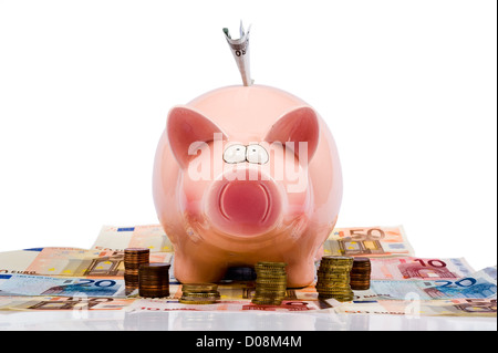 Un enregistrement de porc est debout entre le papier-monnaie et pièces euro Banque D'Images