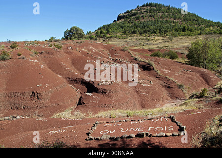 INSCRIPTION DE PIERRES BLANCHES NOUS NE VIT QU'UNE FOIS SUR L'ARGILE ROUGE RICHE EN OXYDE DE FER LA TERRE ROUGE PRÈS DU LAC DU SALAGOU Hérault (34) Banque D'Images