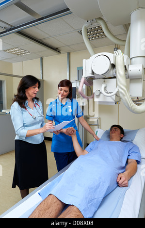 Doctor and nurse talking to patient et rassurant qui est allongé sur une table à rayons X lors de l'enregistrement patient notes Banque D'Images