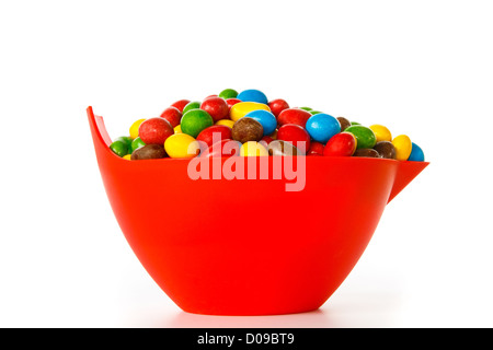 Bol avec des bonbons de chocolat colorés contre fond blanc Banque D'Images