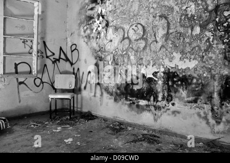 Chaise dans le coin d'une décadence avec mur moisi de déroulage. Noir et blanc. Banque D'Images