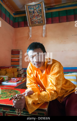 Jeune moine bouddhiste Sherab juine à l'intérieur de quartiers personnels, Sangrgompa Monastère, Lac Namtso, Tibet, Chine Banque D'Images